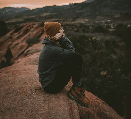 a women sitting on a cliff and dreaming about her next adventure